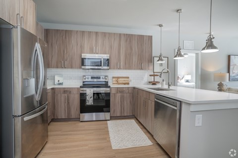 A modern kitchen with wooden cabinets and stainless steel appliances.at The Delaney at East Park Apartments, Kennesaw